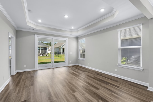 spare room featuring crown molding, a raised ceiling, baseboards, and wood finished floors