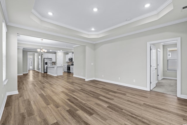 unfurnished living room featuring baseboards, wood finished floors, and a raised ceiling