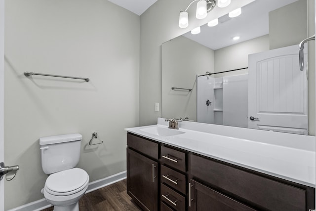 full bathroom with a shower, wood finished floors, baseboards, vanity, and toilet