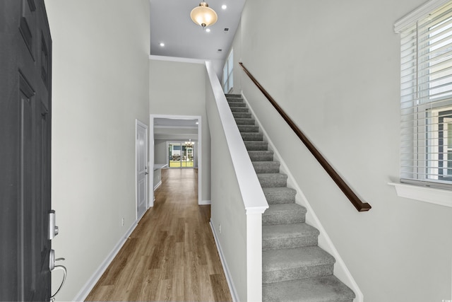 stairway with baseboards, recessed lighting, a towering ceiling, and wood finished floors
