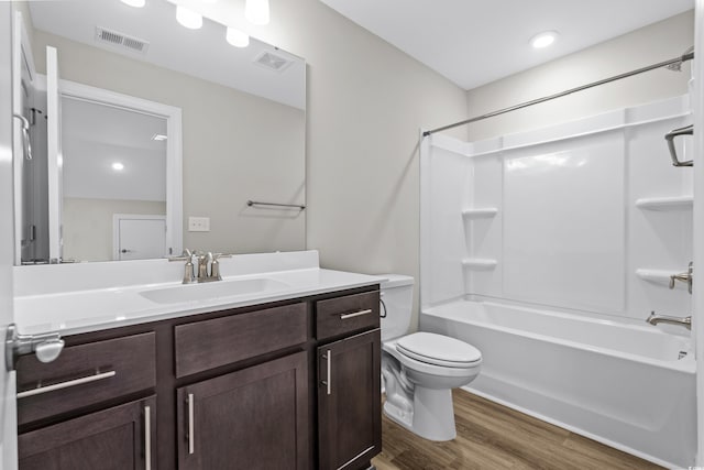 bathroom with vanity, shower / bathtub combination, toilet, wood finished floors, and visible vents