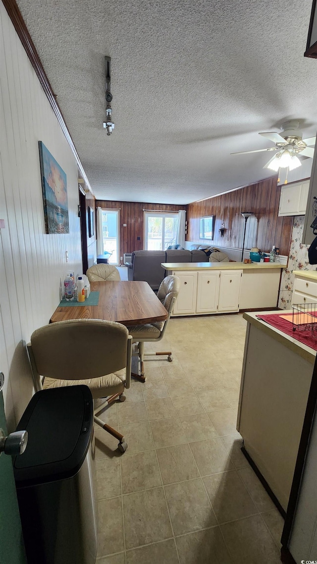 9540 Shore Dr Unit 1N, Myrtle Beach, SC 29572 - kitchen with wood walls, a textured ceiling, white cabinets, and a ceiling fan