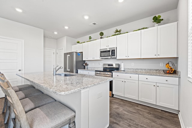 3968 Hibiscus Dr, Little River, SC 29566 - kitchen with stainless steel appliances, a sink, an island with sink, dark wood-style flooring, and white cabinetry