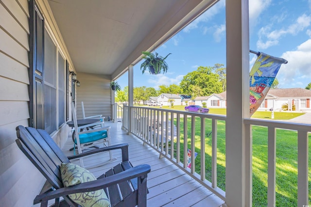 wooden deck with a lawn, a porch, and a residential view
