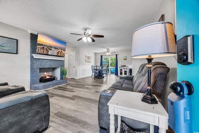 living area with ceiling fan, wood finished floors, and a fireplace