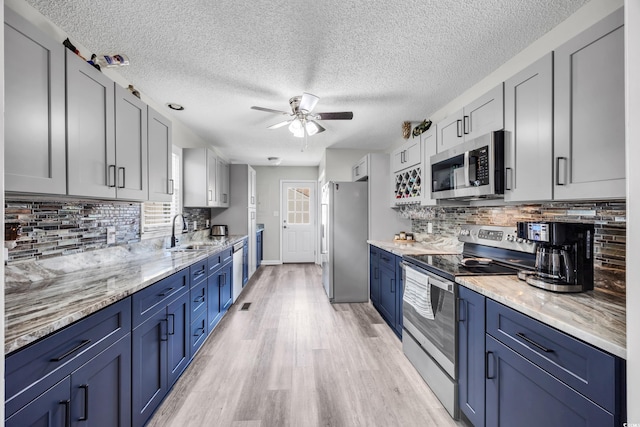 kitchen featuring a sink, appliances with stainless steel finishes, ceiling fan, and blue cabinetry