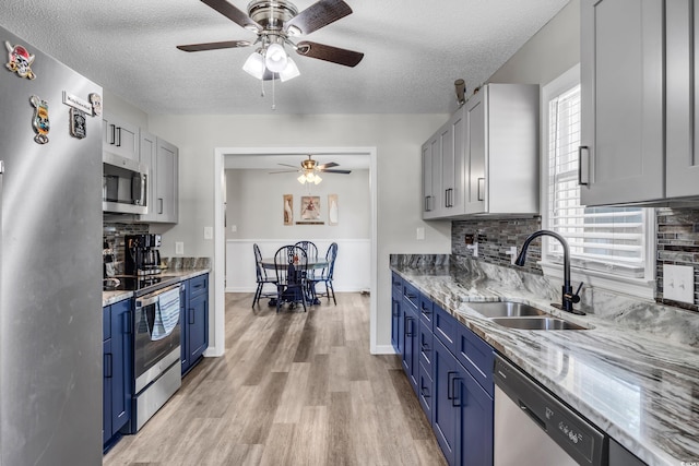 kitchen featuring stainless steel appliances, blue cabinetry, a sink, and a textured ceiling