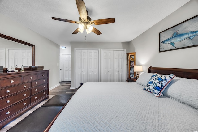 bedroom with two closets, a ceiling fan, and baseboards