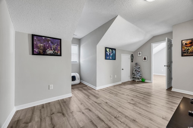 additional living space featuring a textured ceiling and wood finished floors