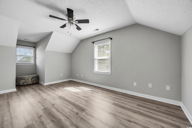 additional living space with a textured ceiling, ceiling fan, vaulted ceiling, and wood finished floors