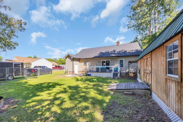 back of house featuring fence, a chimney, a yard, and a deck