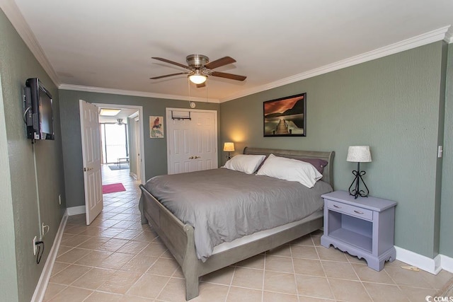 bedroom with a closet, ornamental molding, light tile patterned flooring, baseboards, and a ceiling fan
