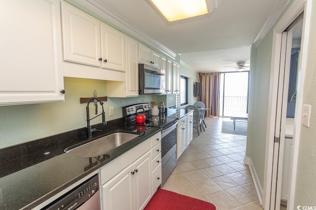 kitchen featuring crown molding, dark stone counters, white cabinets, a sink, and stainless steel appliances