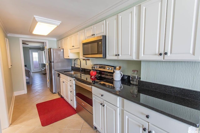 kitchen with crown molding, white cabinetry, a sink, appliances with stainless steel finishes, and light tile patterned floors