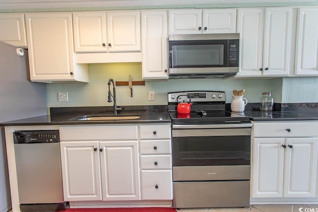 kitchen with dark stone counters, stainless steel appliances, white cabinetry, and a sink