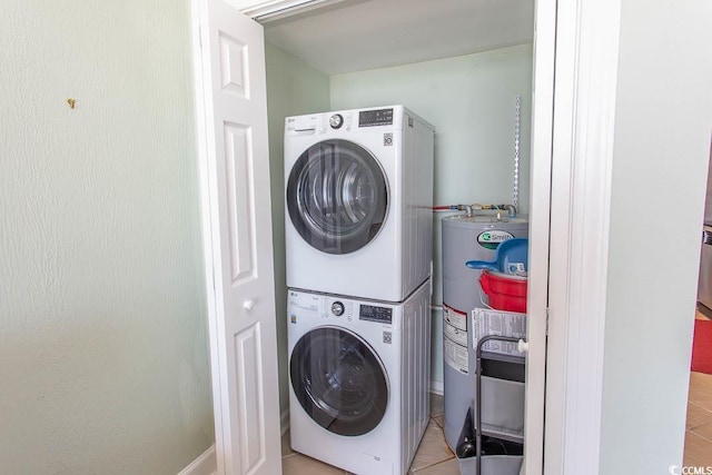 laundry area featuring water heater, light tile patterned floors, stacked washer / drying machine, and laundry area