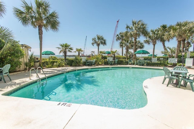 community pool with a patio area and fence