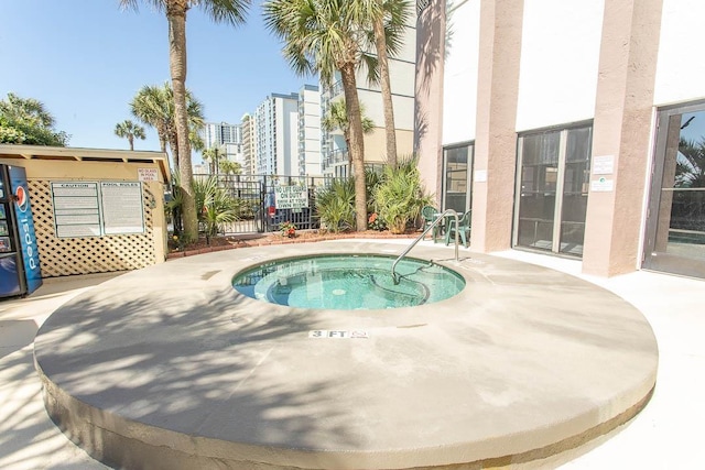 view of swimming pool featuring fence and a hot tub