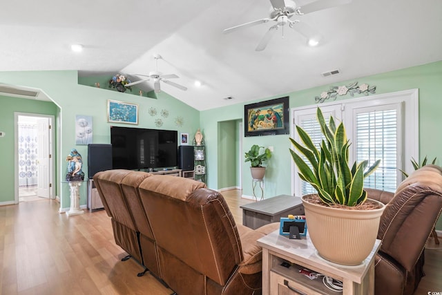 living area with visible vents, light wood-style floors, baseboards, a ceiling fan, and vaulted ceiling