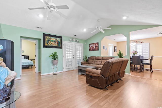 living room with light wood-style floors, ceiling fan with notable chandelier, baseboards, lofted ceiling, and visible vents