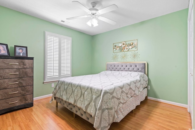 bedroom with baseboards, ceiling fan, wood finished floors, and visible vents