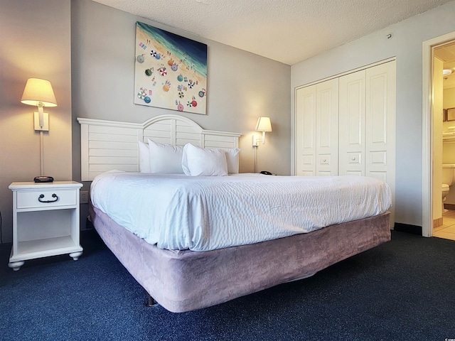 bedroom featuring carpet flooring, a textured ceiling, ensuite bathroom, and a closet