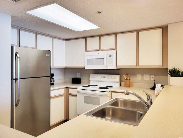 kitchen featuring a textured ceiling, a sink, light countertops, white cabinets, and white appliances