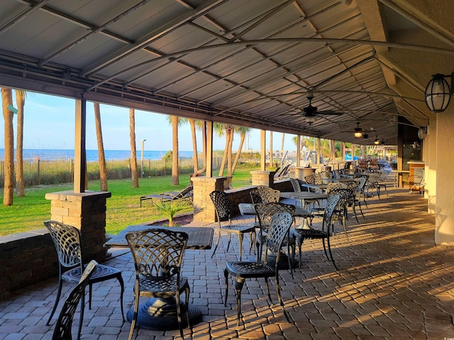 view of patio with a water view, ceiling fan, and outdoor dining space