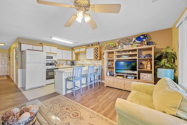 living area featuring light wood-type flooring and a ceiling fan