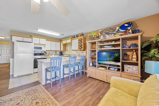 living room featuring light wood-style flooring, a textured ceiling, and a ceiling fan