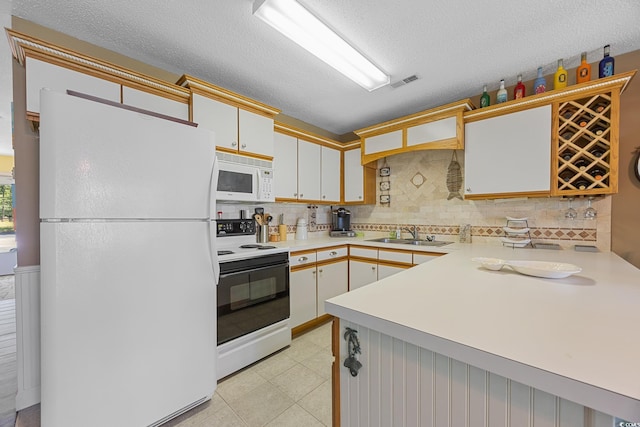 kitchen featuring white appliances, a sink, light countertops, decorative backsplash, and a textured ceiling