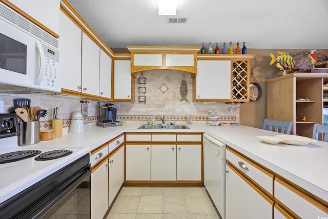 kitchen with white appliances, a sink, light countertops, tasteful backsplash, and a textured ceiling