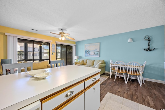 kitchen featuring a textured ceiling, a ceiling fan, light countertops, white cabinets, and baseboards