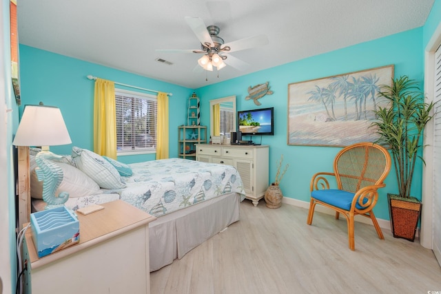 bedroom with light wood-style floors, baseboards, and a ceiling fan