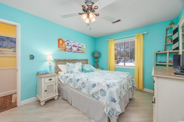 bedroom with light wood-style flooring, baseboards, and a ceiling fan