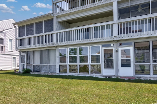 back of house with a balcony, a yard, and a sunroom