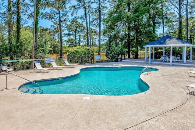 community pool with a gazebo, fence, a patio area, and view of scattered trees
