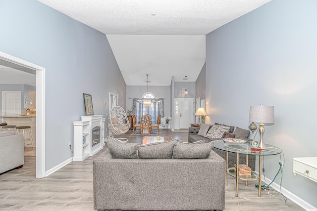 living room with baseboards, light wood finished floors, and high vaulted ceiling
