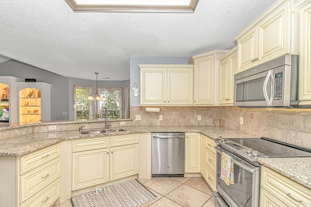 kitchen with backsplash, stainless steel appliances, a sink, and cream cabinetry