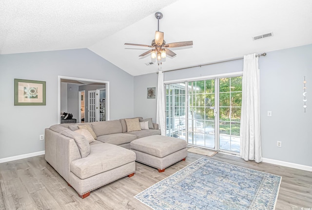 living room featuring visible vents, french doors, a ceiling fan, light wood-type flooring, and vaulted ceiling