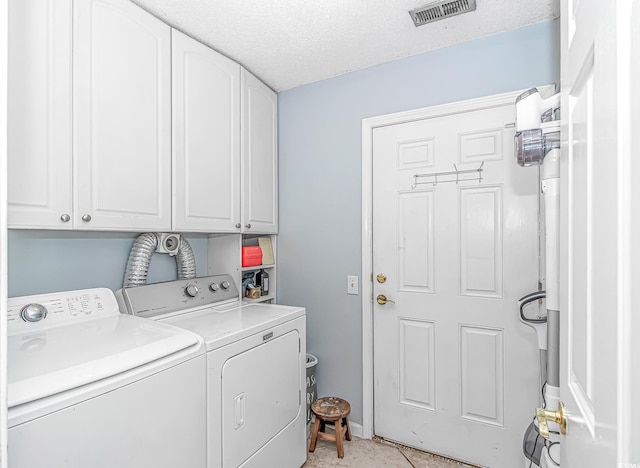 laundry room featuring cabinet space, a textured ceiling, visible vents, and washer and dryer