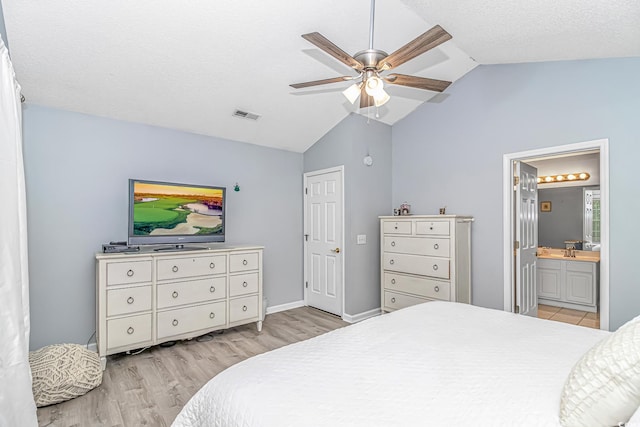 bedroom featuring visible vents, a sink, lofted ceiling, light wood-style floors, and ensuite bathroom