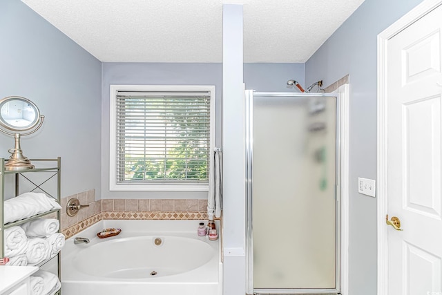 bathroom with a textured ceiling, a bath, and a stall shower