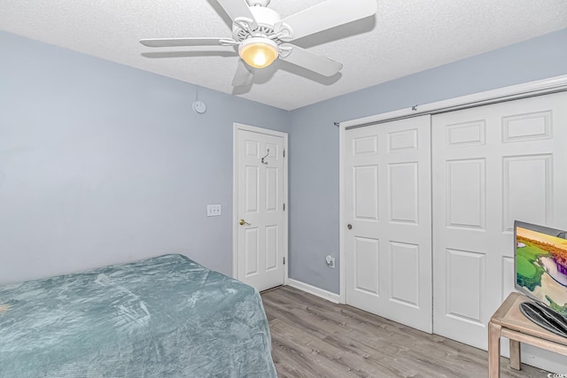 bedroom featuring a textured ceiling, ceiling fan, a closet, and wood finished floors