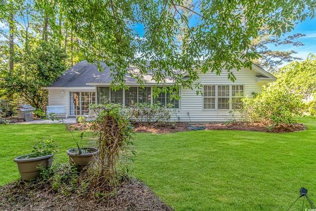 rear view of house with a yard, a patio, and a sunroom