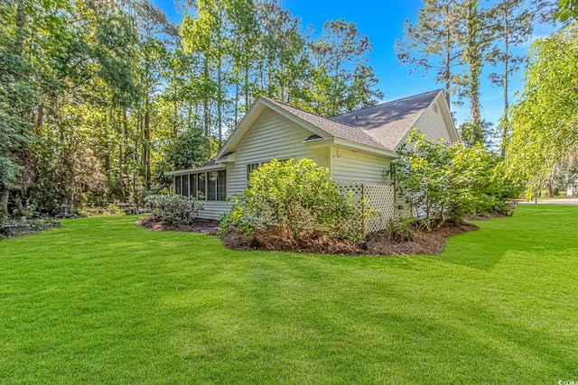 view of home's exterior with a sunroom, a shingled roof, and a yard