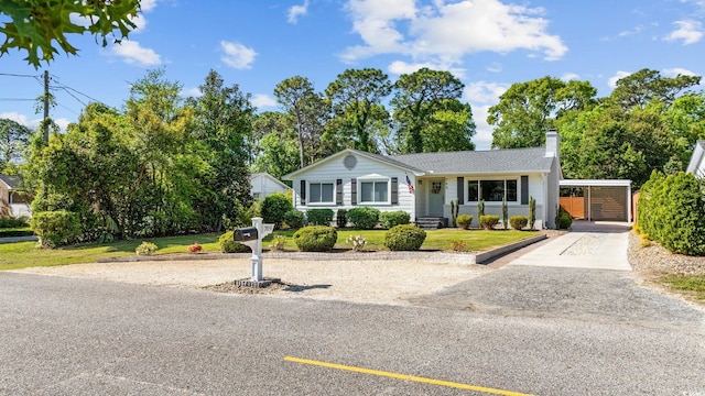 single story home featuring a carport, a chimney, a front yard, and aphalt driveway