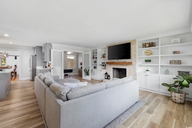 living area with crown molding, light wood-style flooring, a brick fireplace, and ceiling fan