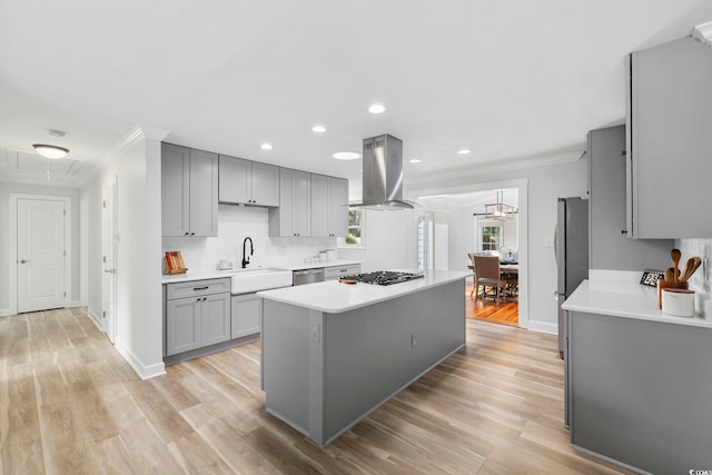 kitchen with ornamental molding, a center island, gray cabinets, island exhaust hood, and a sink