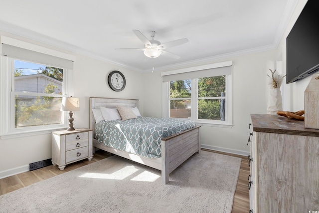 bedroom featuring baseboards, wood finished floors, and multiple windows